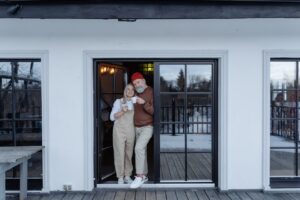An elderly couple is standing at the door to their new home, purchased thanks to mortgages for seniors and retirees.
