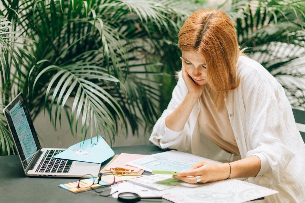 Construction Loans: The Complete Guide 2 A woman sitting at a table with her laptop and documents to see if she's eligible for construction loans.