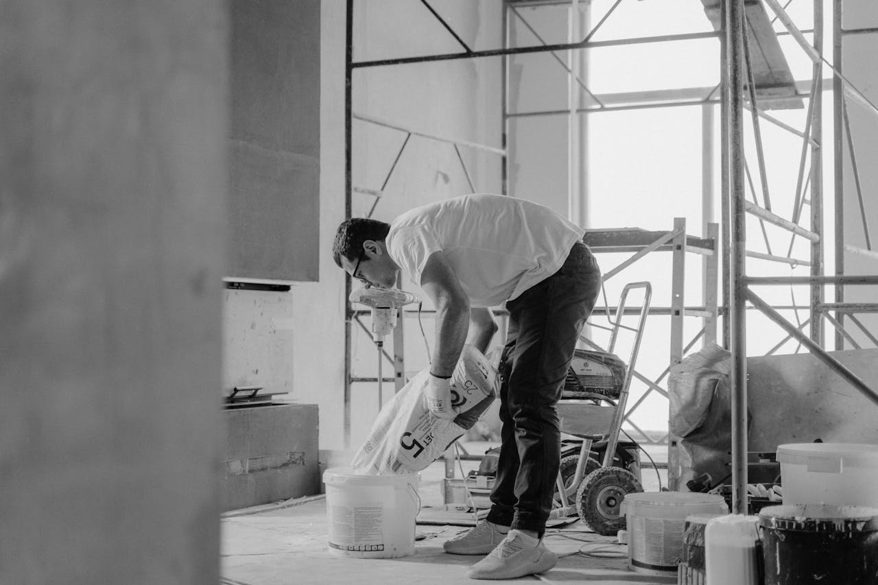 The Digital Deed 3 A man who purchased a fixer upper using DSCR loans for fix-and-flip projects is pouring building material into a bucket.