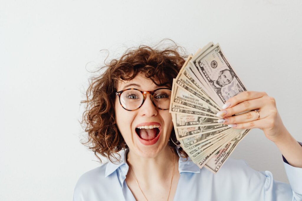 Interest Rate Cuts: Refinancing, Rates and What You Need to Know 2 A woman is smiling while holding up the money she saved from refinancing during interest rate cuts.