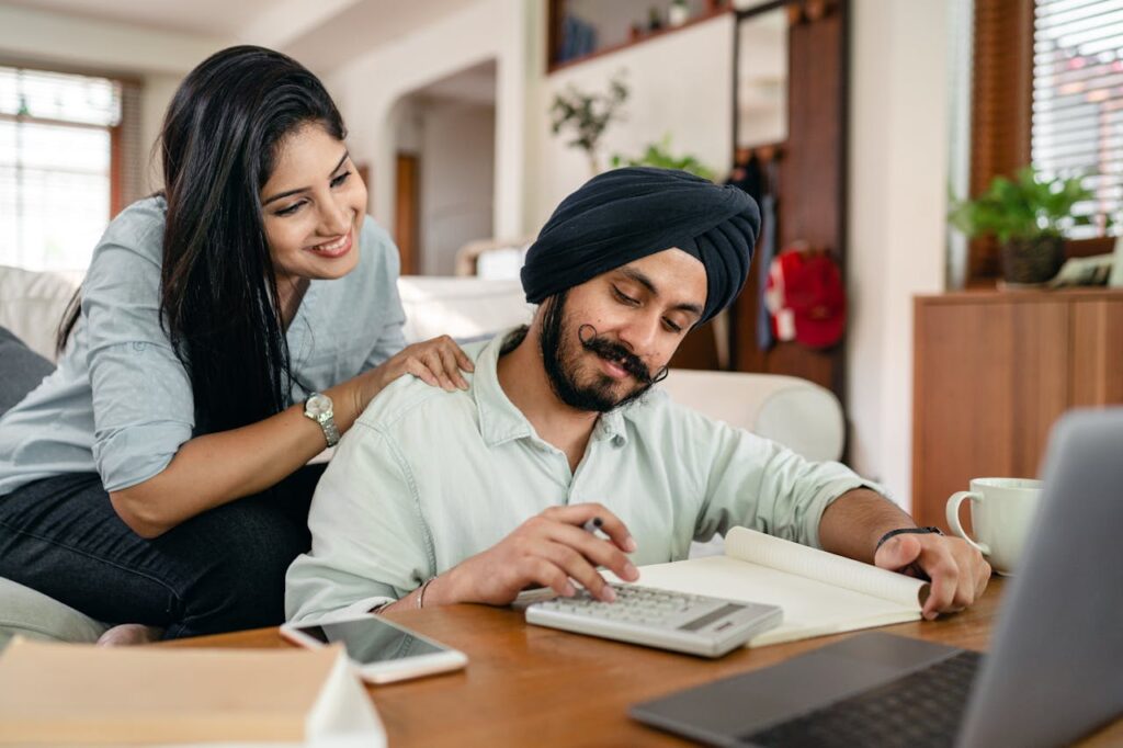 Interest Rate Cuts: Refinancing, Rates and What You Need to Know 4 A South-Asian couple is smiling while evaluating their finances and making their long-term plan before interest rate cuts happen.