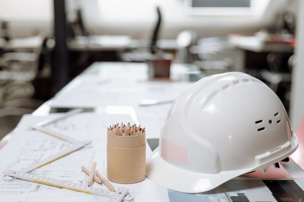 Construction Loan Oregon: Maximize Your Building Potential 3 Construction plans with colored pencils and a white hard hat on top.