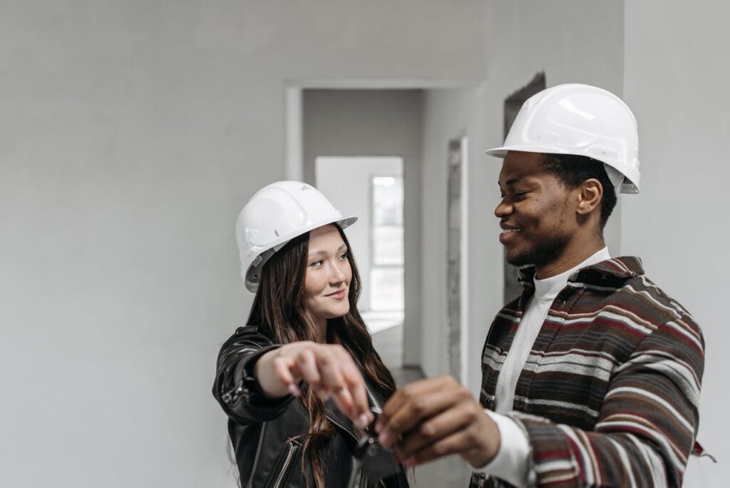 Construction Loan Oregon: Maximize Your Building Potential 4 A young couple wearing white hard hats is holding the keys to their new-build home that was financed with a construction loan Oregon.