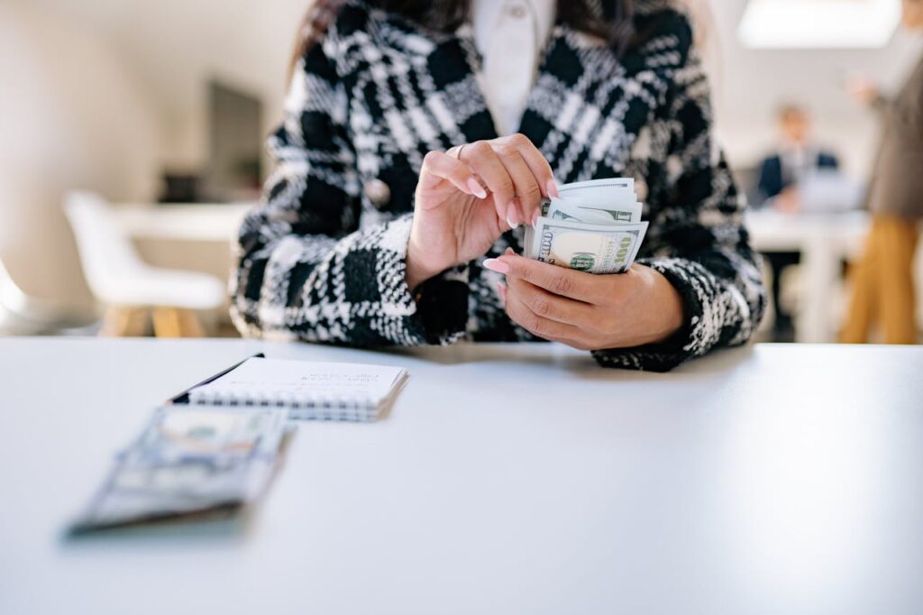 Real Estate Investment Loans: The Ultimate 2025 Guide 3 A woman is counting out $100 bank notes to make sure she has a financial cushion before considering any real estate investment loans.