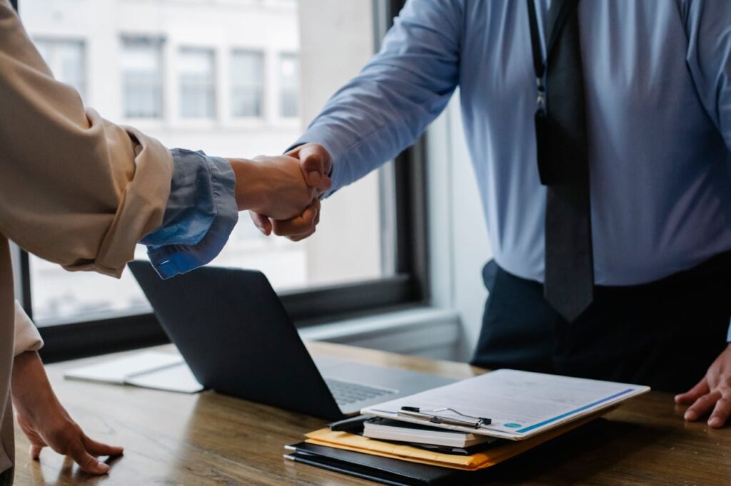Deed of Trust vs Mortgage: Simplifying the Basics for Buyers 1 A loan officer is shaking hands with a new homeowner after paperwork was completed and explaining the difference between deed of trust vs mortgage.
