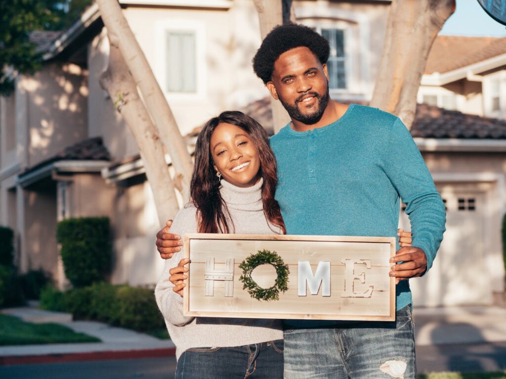 How Rising Rates Impact Home Equity Loans and Cash-Out Refinancing 2 A young couple is holding a sign in front of their house that says "home."