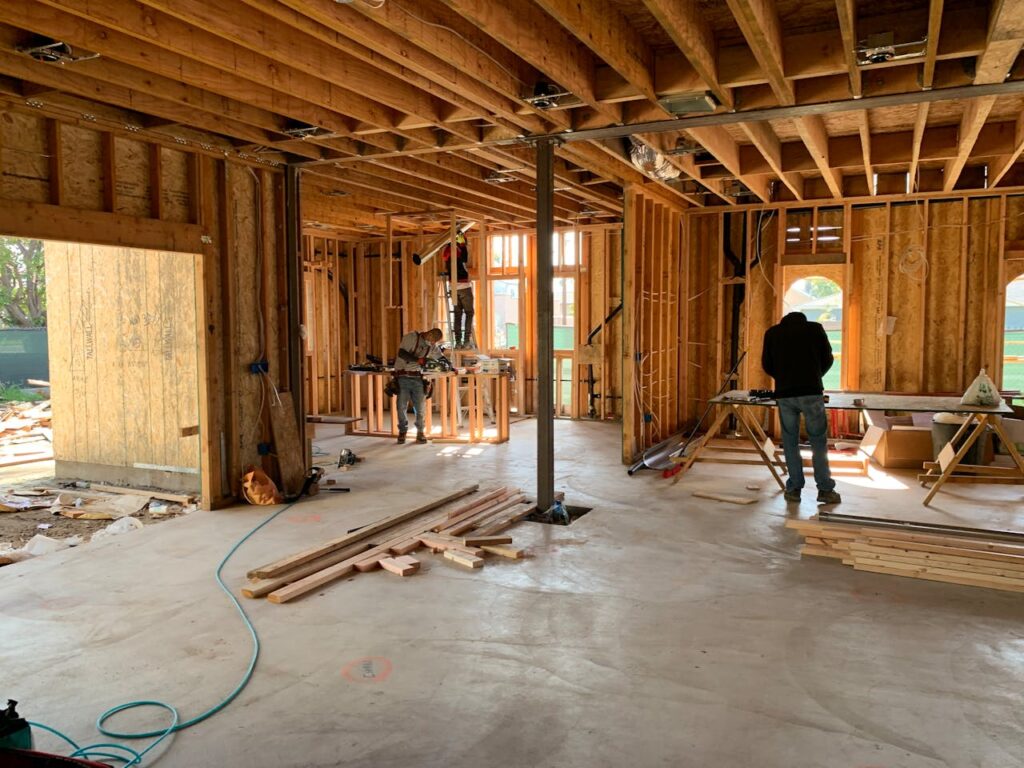 FHA Construction Loan Basics: A Simple Guide 2 Three men sawing planks of wood and putting together the frame of a new home financed with an FHA construction loan.