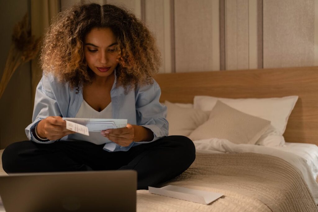 Mortgage Statements Made Easy: A Quick How-To Guide 2 A woman is sitting on her bed reading her mortgage statement she received in the mail in front of her laptop.