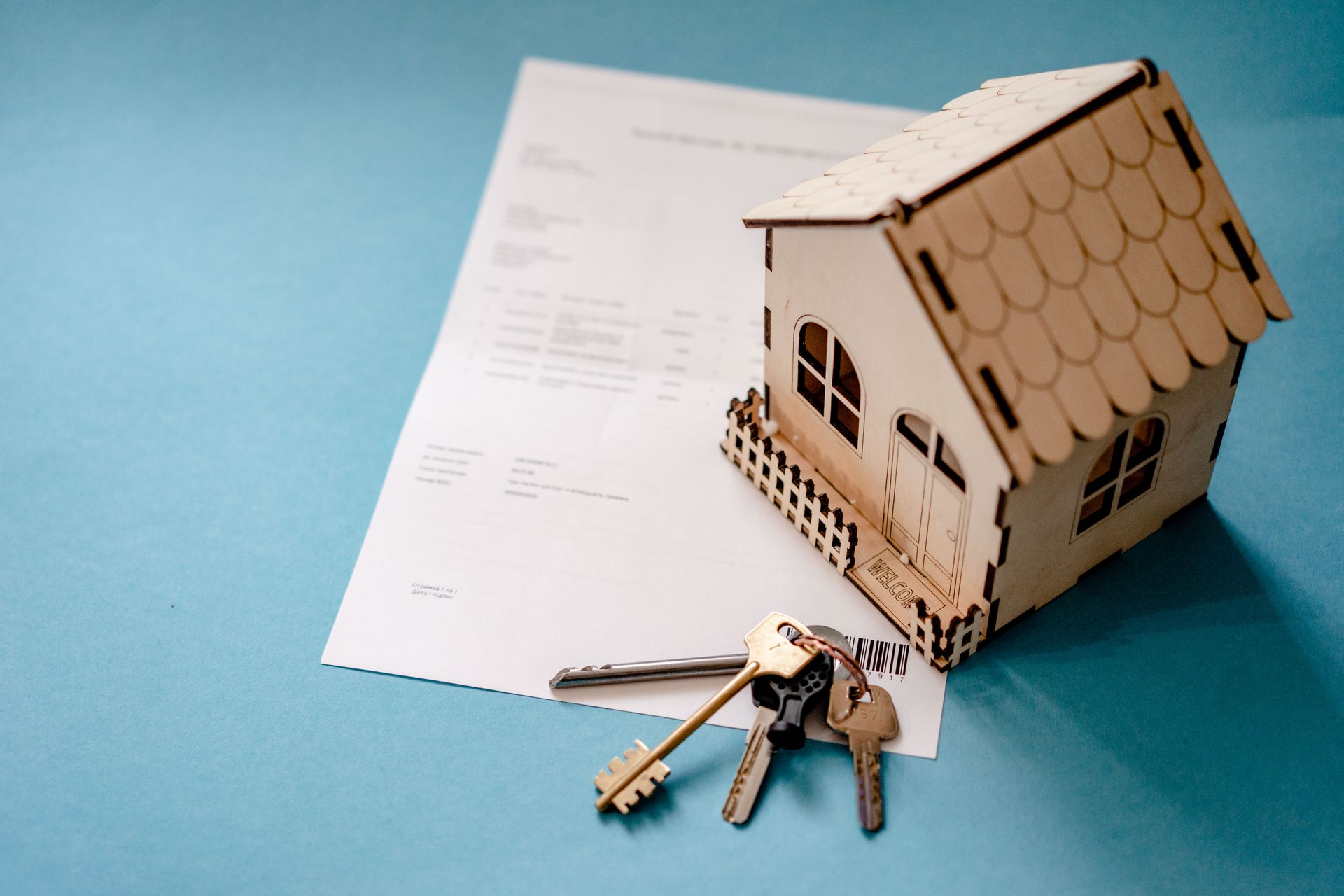 The Digital Deed 20 Wooden house model, keys and a loan contract on a table