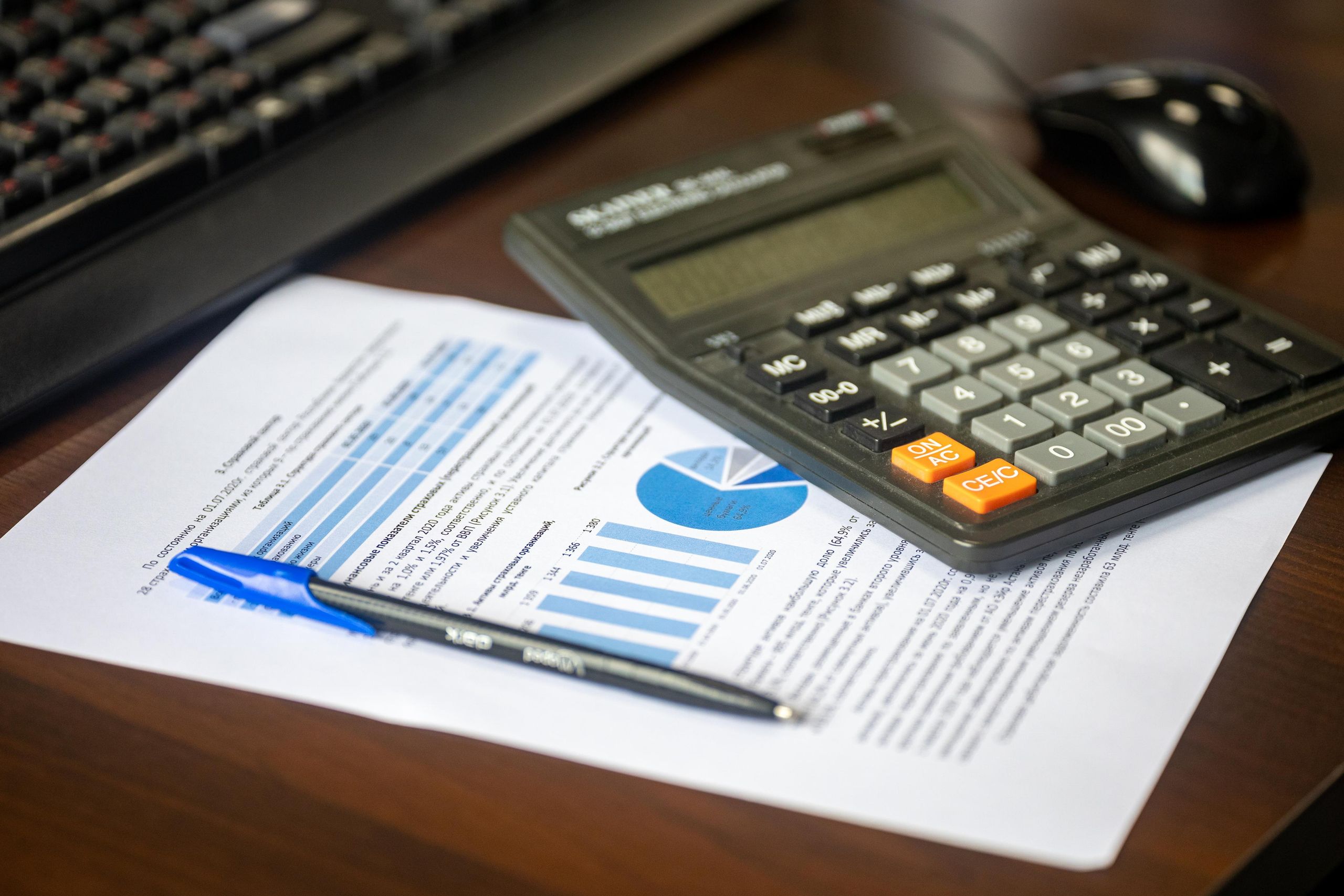 Non-QM Loans: The Complete Guide (2025) 1 A calculator resting on a printed financial report with bar and pie charts, illustrating alternative income documentation review for non-QM loans